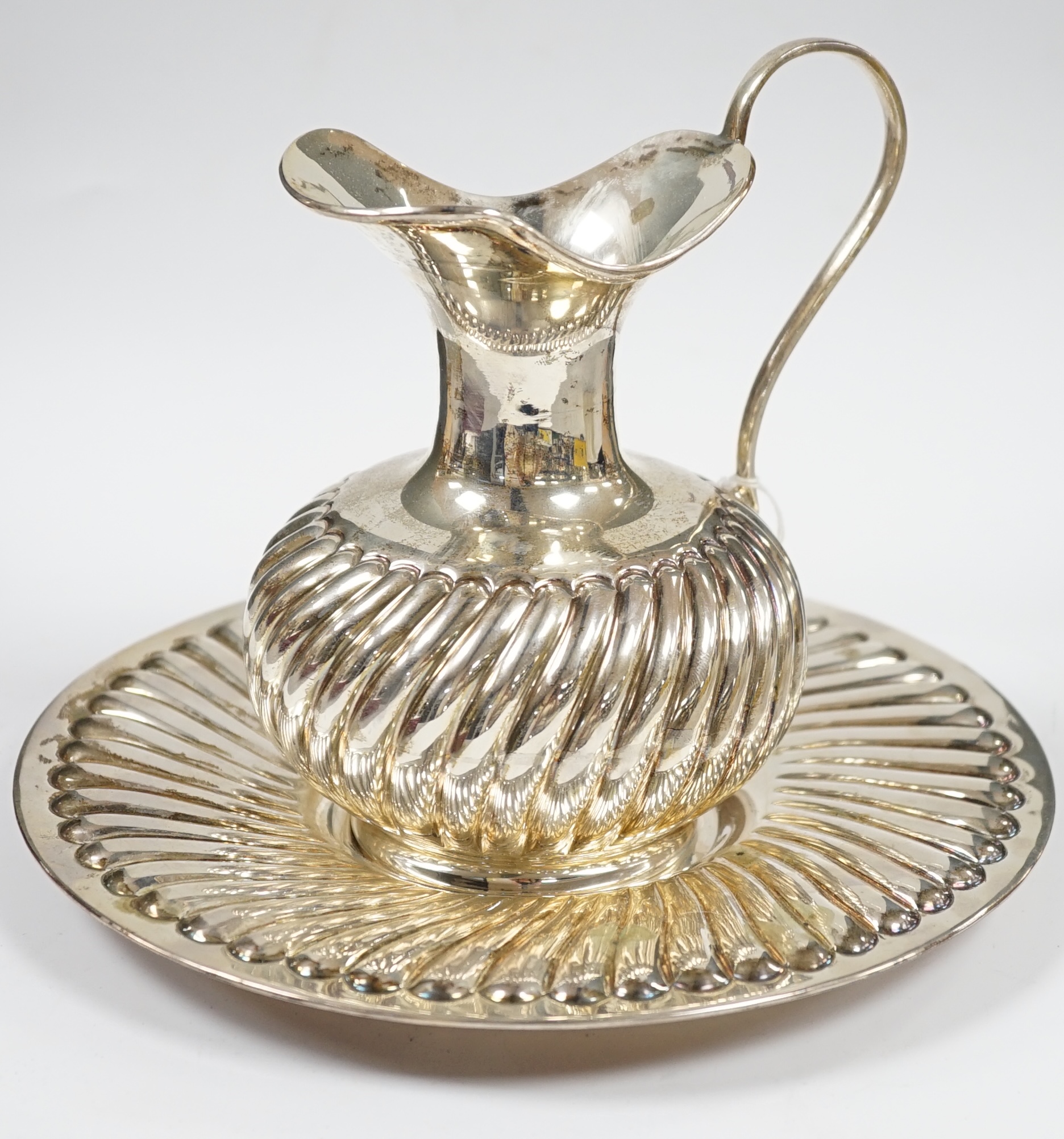 A modern 925 ewer and stand, with wrythened fluted decoration, stand diameter 22.3cm, 18.2oz. Condition - fair